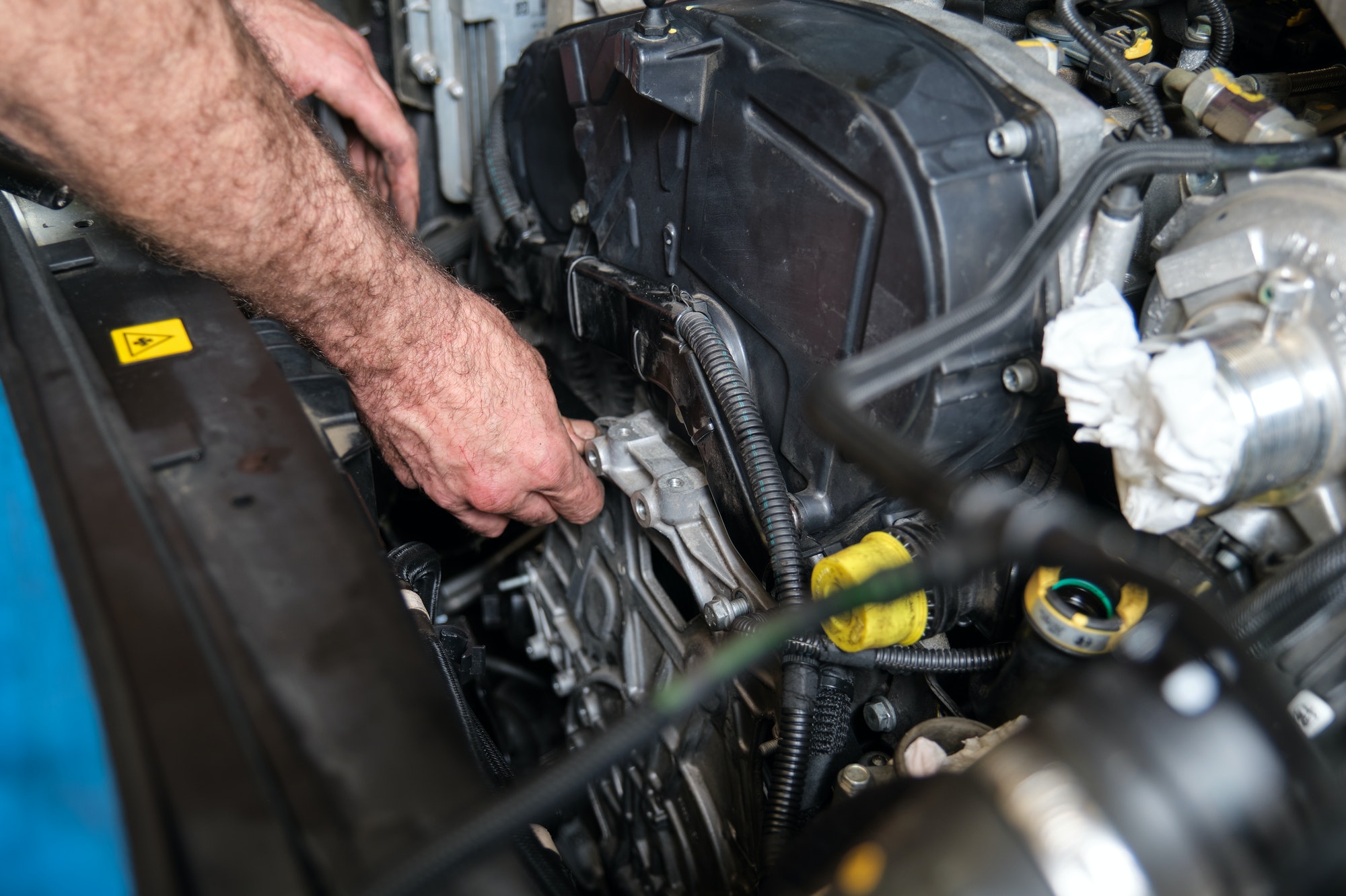 Auto mechanic hands screws the engine mount after replace the timing belt.