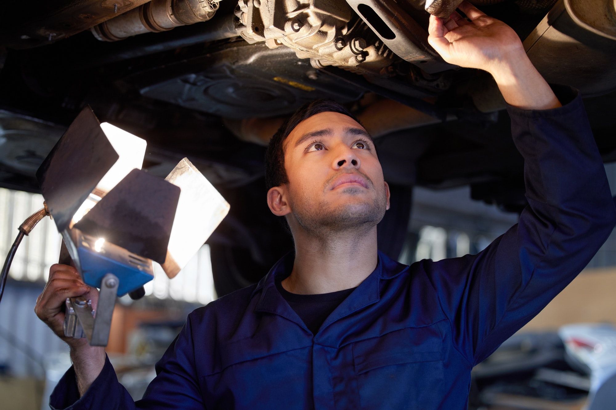 Cropped shot of a handsome young male mechanic working on the engine of a car during a service