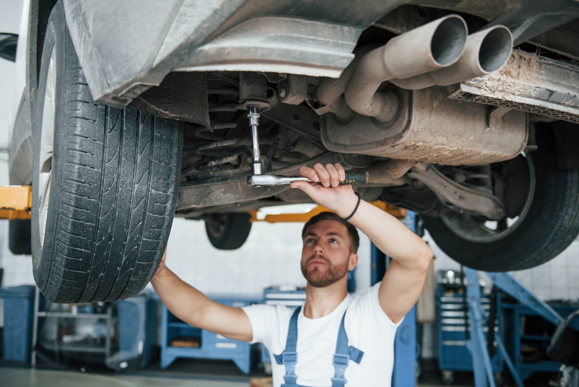 Shock absorbers on photo. Employee in the blue colored uniform works in the automobile salon