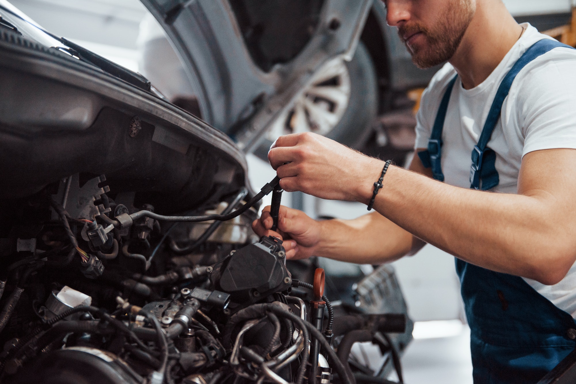 Wire for clutch in hands. Employee in the blue colored uniform works in the automobile salon